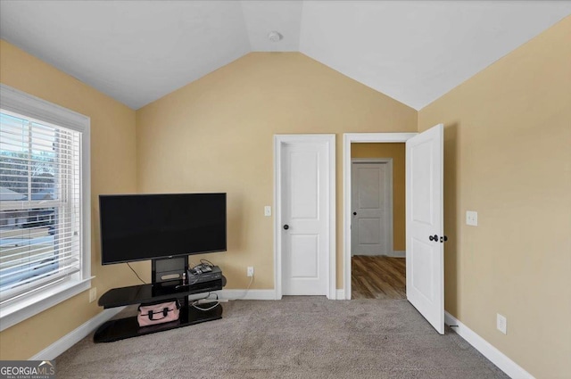 carpeted bedroom with lofted ceiling and baseboards