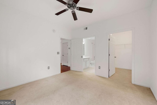 unfurnished bedroom with a walk in closet, a closet, visible vents, carpet flooring, and connected bathroom