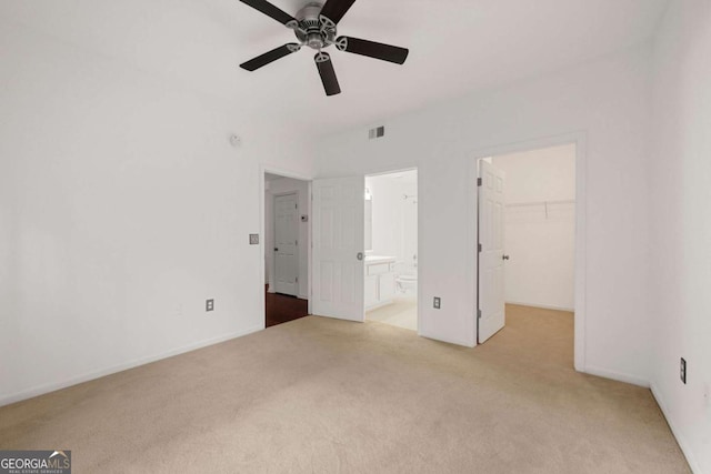 unfurnished bedroom featuring carpet floors, a walk in closet, visible vents, connected bathroom, and ceiling fan