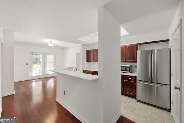 kitchen with light wood-style flooring, appliances with stainless steel finishes, light countertops, french doors, and a sink