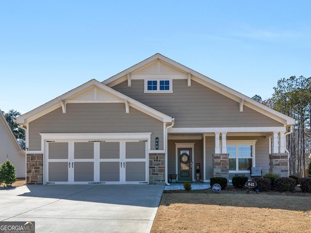 craftsman inspired home featuring a garage, stone siding, covered porch, and driveway