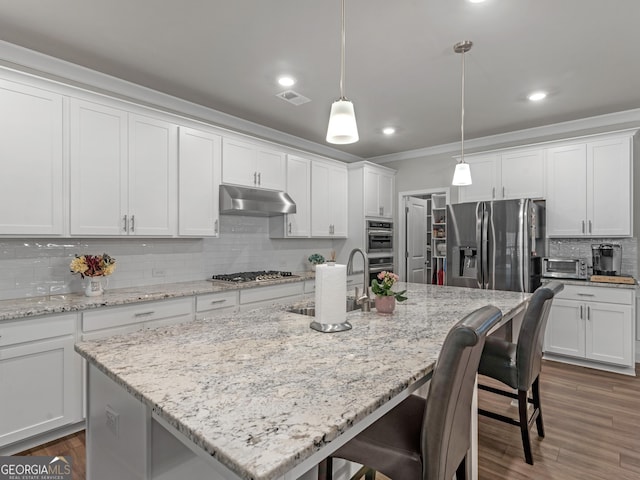 kitchen with visible vents, appliances with stainless steel finishes, a kitchen breakfast bar, under cabinet range hood, and a sink