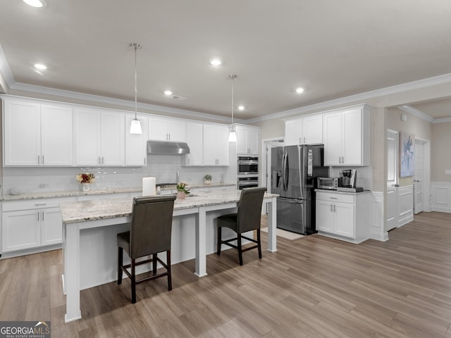 kitchen featuring white cabinets, appliances with stainless steel finishes, a center island with sink, and under cabinet range hood