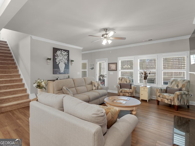 living area with stairway, crown molding, visible vents, and wood finished floors