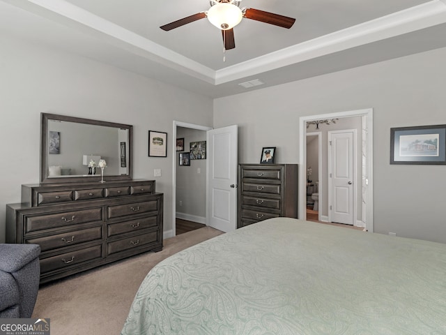 carpeted bedroom featuring baseboards, visible vents, a raised ceiling, and a ceiling fan