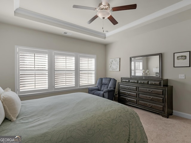 bedroom featuring visible vents, baseboards, ceiling fan, carpet, and a tray ceiling