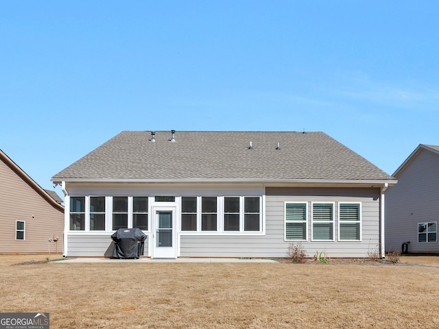 rear view of property with a sunroom, a shingled roof, and a yard