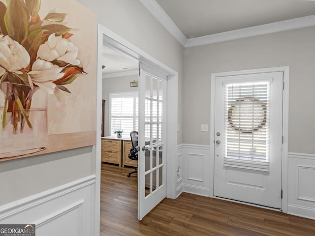 doorway featuring a wainscoted wall, a decorative wall, crown molding, and wood finished floors