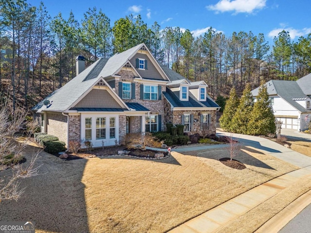 view of front of home featuring stone siding, a front lawn, and a chimney