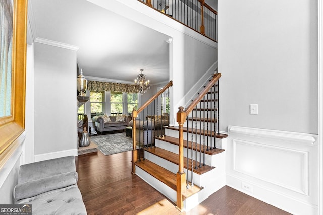 staircase featuring a chandelier, crown molding, and wood finished floors