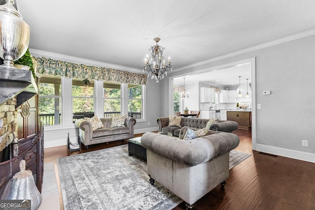 living area with wood finished floors, crown molding, baseboards, and an inviting chandelier