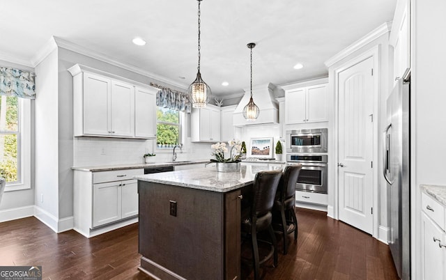 kitchen featuring a sink, white cabinets, appliances with stainless steel finishes, a center island, and crown molding