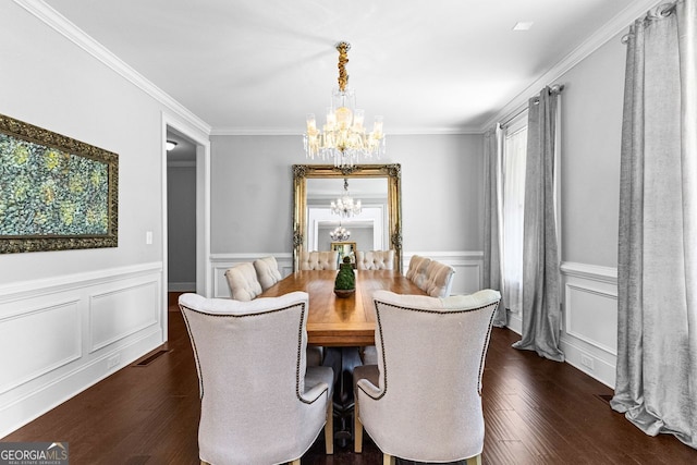 dining area featuring a wainscoted wall, ornamental molding, dark wood finished floors, and a notable chandelier