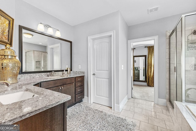 bathroom with vanity, baseboards, visible vents, a shower stall, and tile patterned floors