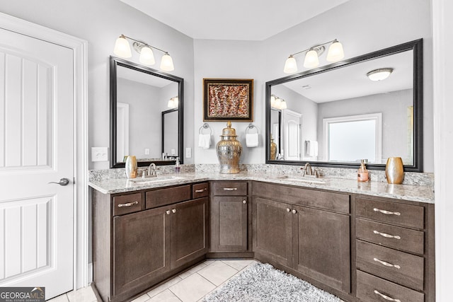 full bath featuring double vanity, tile patterned flooring, and a sink