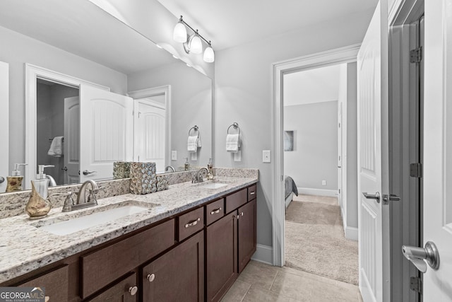 bathroom with tile patterned flooring, a sink, baseboards, and double vanity