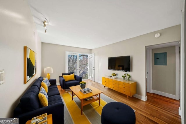 living area featuring electric panel, baseboards, and wood finished floors