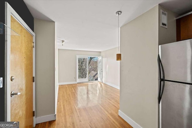 corridor featuring wood finished floors, visible vents, and baseboards