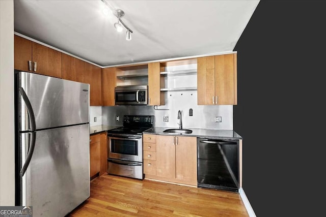 kitchen featuring dark countertops, appliances with stainless steel finishes, light wood-type flooring, open shelves, and a sink