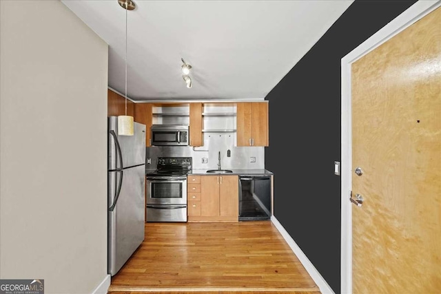 kitchen featuring pendant lighting, light wood finished floors, open shelves, appliances with stainless steel finishes, and a sink