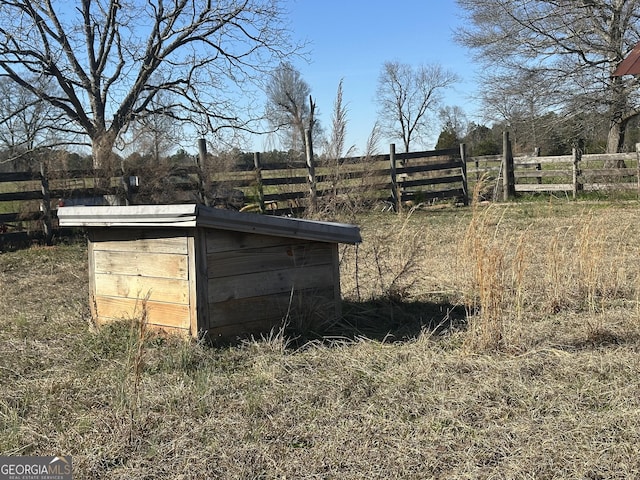 view of outbuilding with fence, an outdoor structure, and a rural view