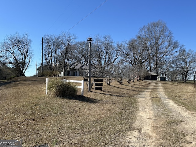 view of street with dirt driveway and street lighting