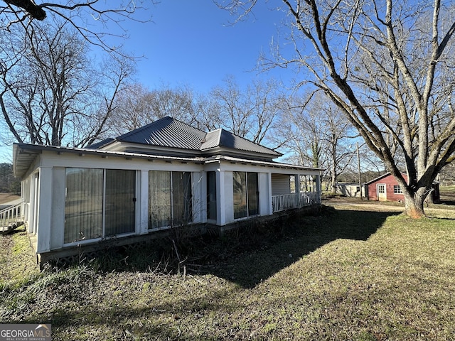 rear view of house featuring a sunroom, metal roof, and a yard