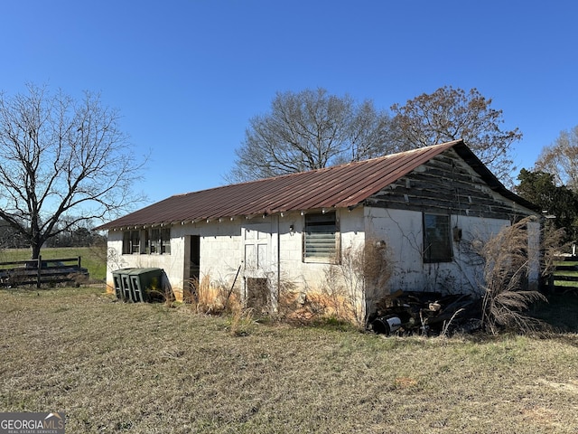 view of property exterior with fence, concrete block siding, metal roof, and a yard