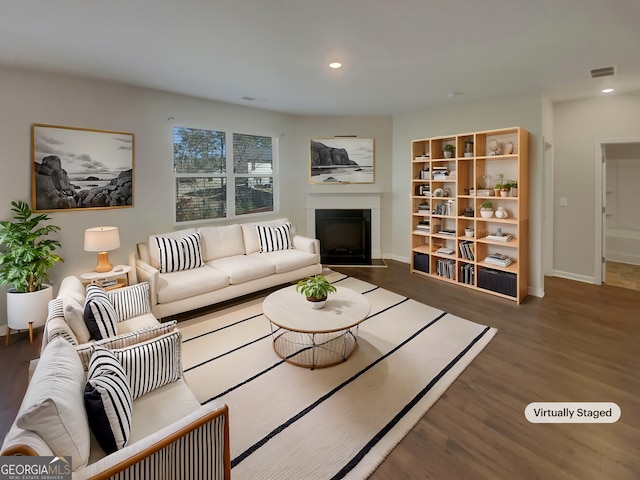 living room featuring a fireplace with flush hearth, visible vents, wood finished floors, and recessed lighting