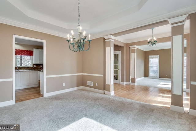 empty room with carpet, a raised ceiling, and an inviting chandelier