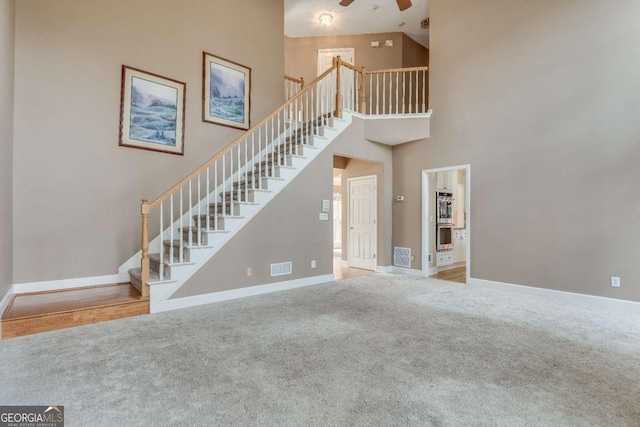 unfurnished living room featuring carpet, visible vents, baseboards, and stairs
