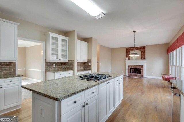 kitchen featuring stainless steel appliances, white cabinets, a fireplace, and light wood-style flooring