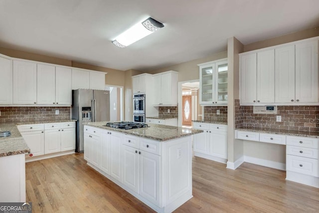 kitchen with appliances with stainless steel finishes, a center island, white cabinetry, and light wood-style flooring