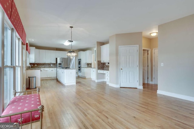 kitchen with a chandelier, stainless steel appliances, tasteful backsplash, and light wood finished floors