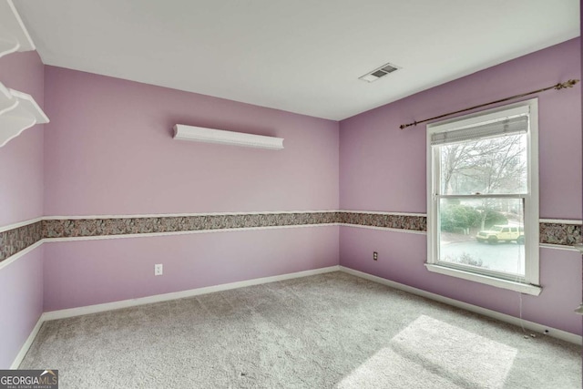 spare room with carpet, visible vents, and baseboards