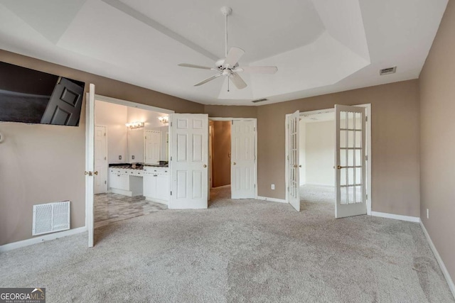 unfurnished bedroom with a tray ceiling, french doors, visible vents, and carpet flooring