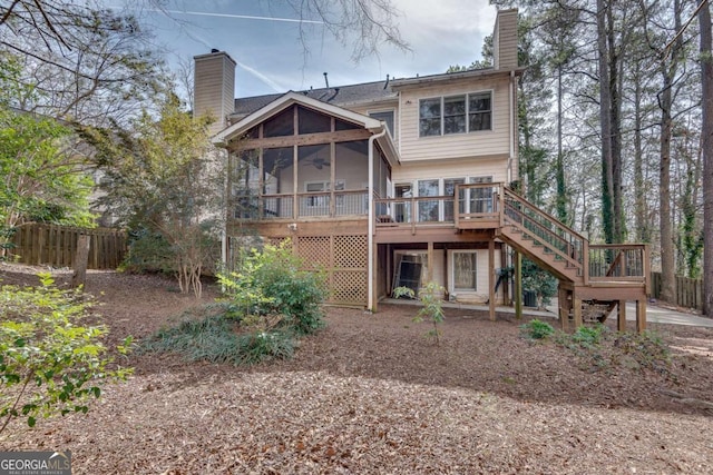 back of property featuring a deck, fence, a sunroom, stairway, and a chimney