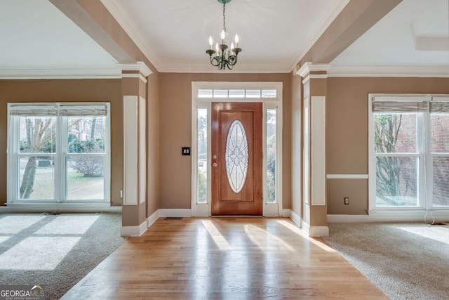 carpeted entryway with a wealth of natural light, decorative columns, and baseboards