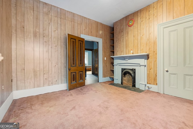 unfurnished living room with carpet floors, a fireplace with flush hearth, and wooden walls