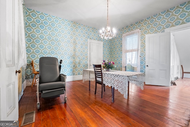 dining area featuring visible vents, a notable chandelier, and wallpapered walls