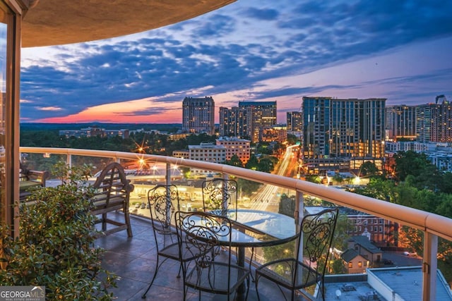 balcony at dusk featuring a view of city