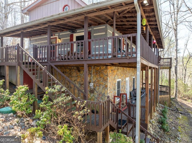 view of side of home with stairs, stone siding, a deck, and board and batten siding