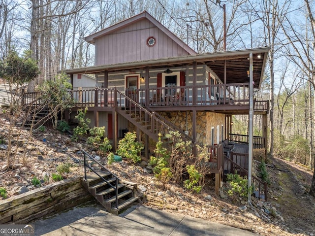 chalet / cabin with stairs, ceiling fan, a deck, and stone siding