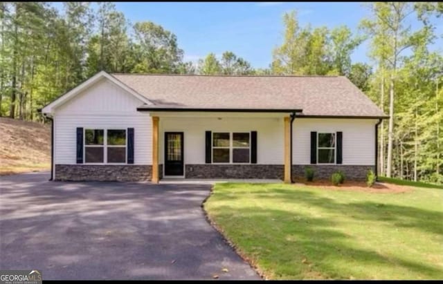 view of front of property featuring driveway, stone siding, and a front yard