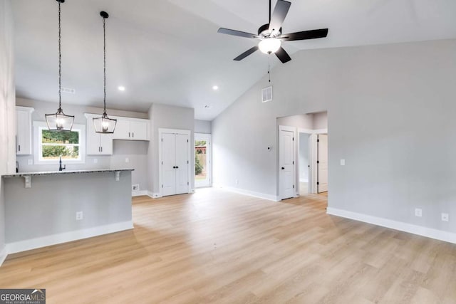 unfurnished living room with a healthy amount of sunlight, visible vents, light wood-style flooring, and baseboards