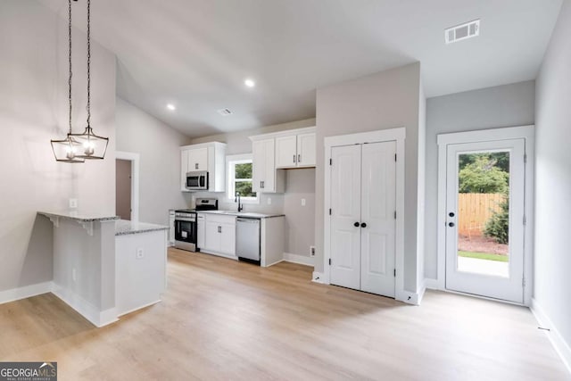 kitchen with visible vents, a peninsula, stainless steel appliances, light wood-style floors, and white cabinetry