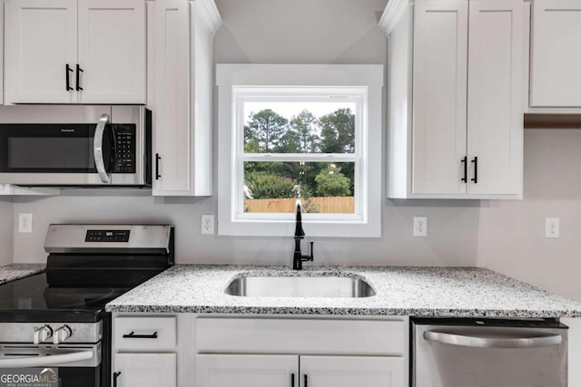 kitchen featuring white cabinetry, appliances with stainless steel finishes, light stone counters, and a sink