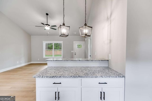 kitchen featuring light stone countertops, white cabinetry, pendant lighting, and light wood-style floors