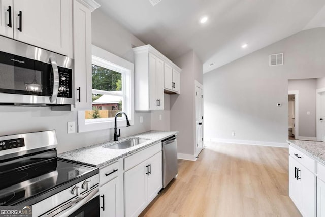 kitchen with visible vents, vaulted ceiling, stainless steel appliances, white cabinetry, and a sink