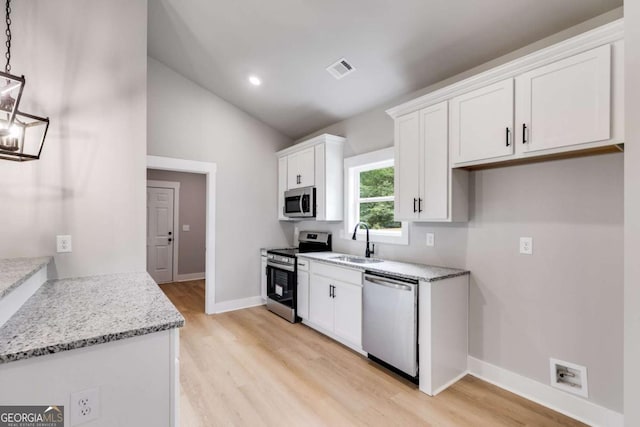 kitchen featuring a sink, white cabinetry, vaulted ceiling, appliances with stainless steel finishes, and light wood finished floors